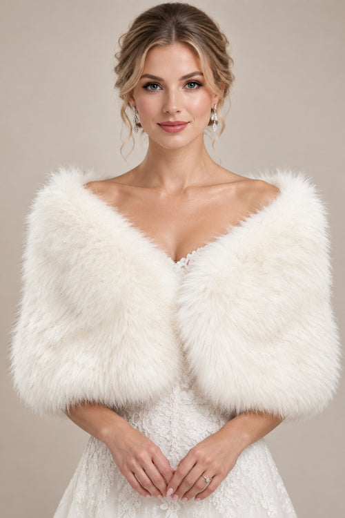 A fluffy white faux-fur cropped wrap or bolero draped on a cream mannequin torso, photographed outdoors with blurred green foliage in the background.